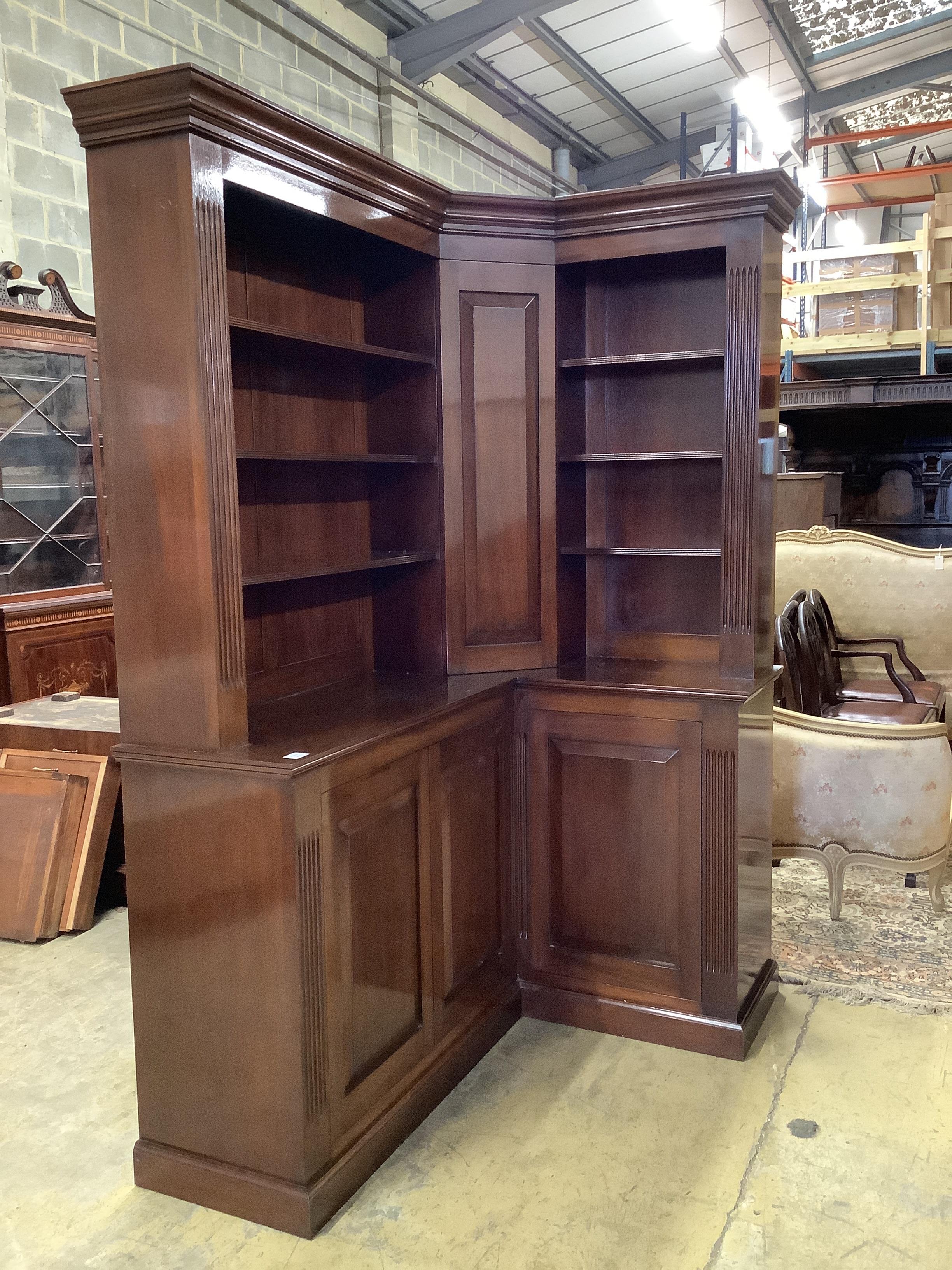 A George III style mahogany corner library bookcase, the mid section incorporating a secret cupboard, width 142cm, depth 102cm, height 213cm